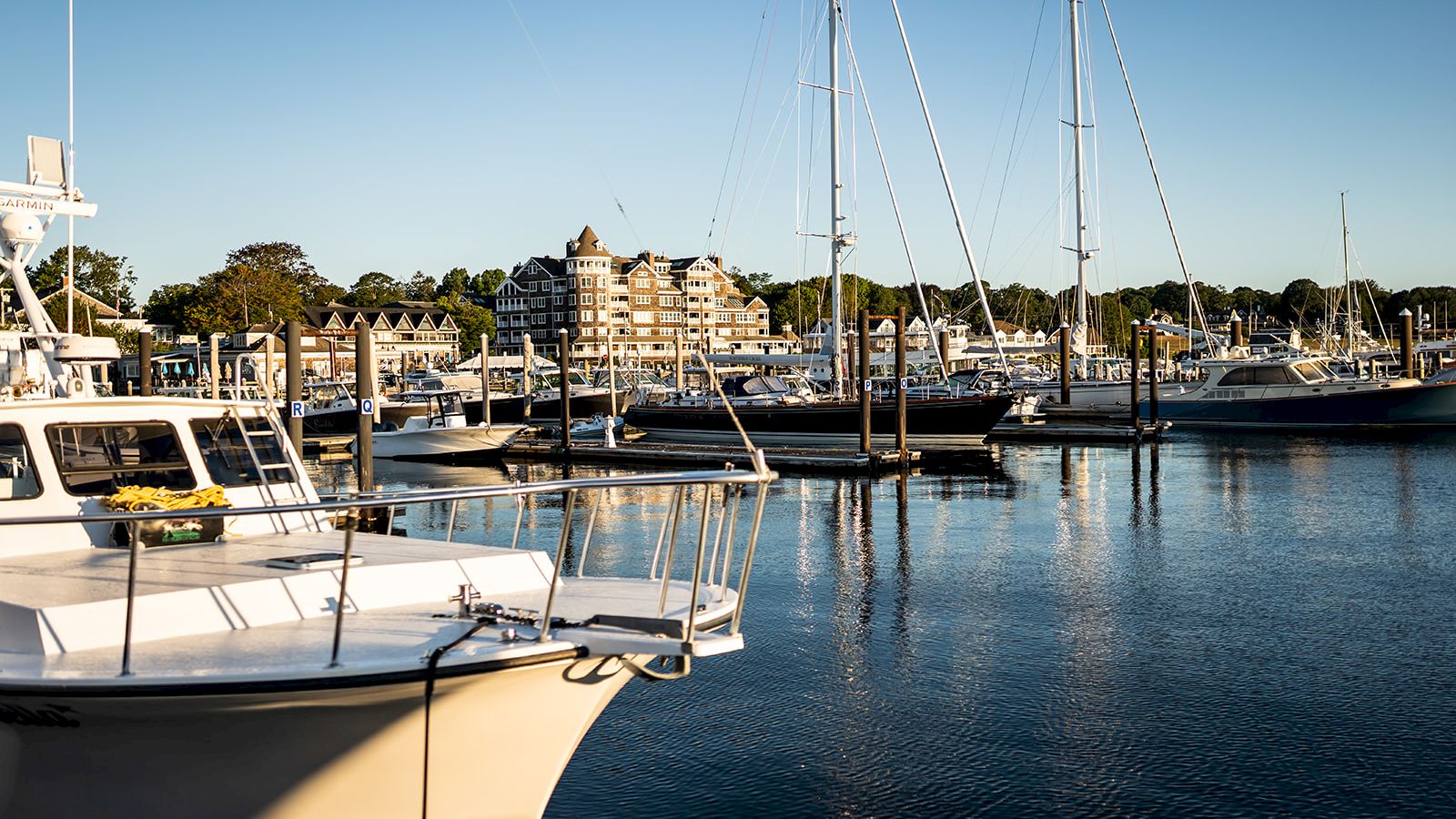 The image shows a marina with multiple boats docked in the water, a charming waterfront building, and a clear sky in the background, ending the sentence.