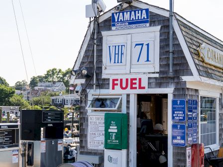 A small fuel shack with &ldquo;FUEL&rdquo; sign, hoses and reels outside, a Yamaha sign on top, and a building with blue and white numbers 71.
